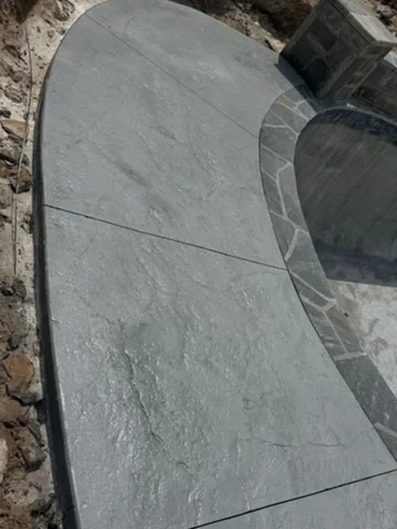Curved stamped concrete walkway edged with natural stone