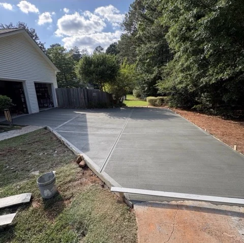 Freshly poured concrete driveway leading to a two car garage